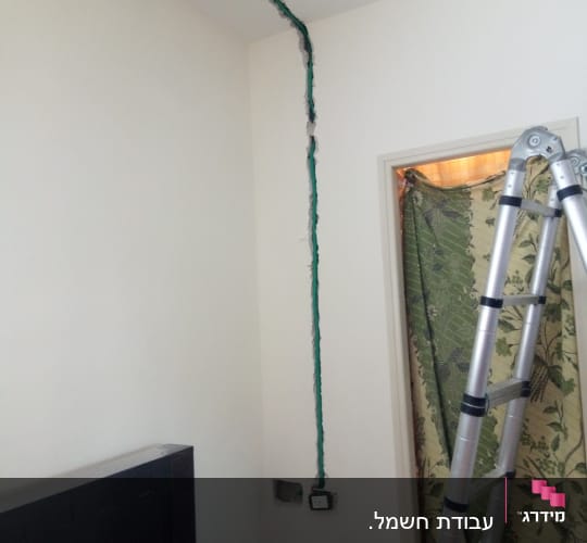 חוטי חשמל חשופים בקיר עם סולם לידם
